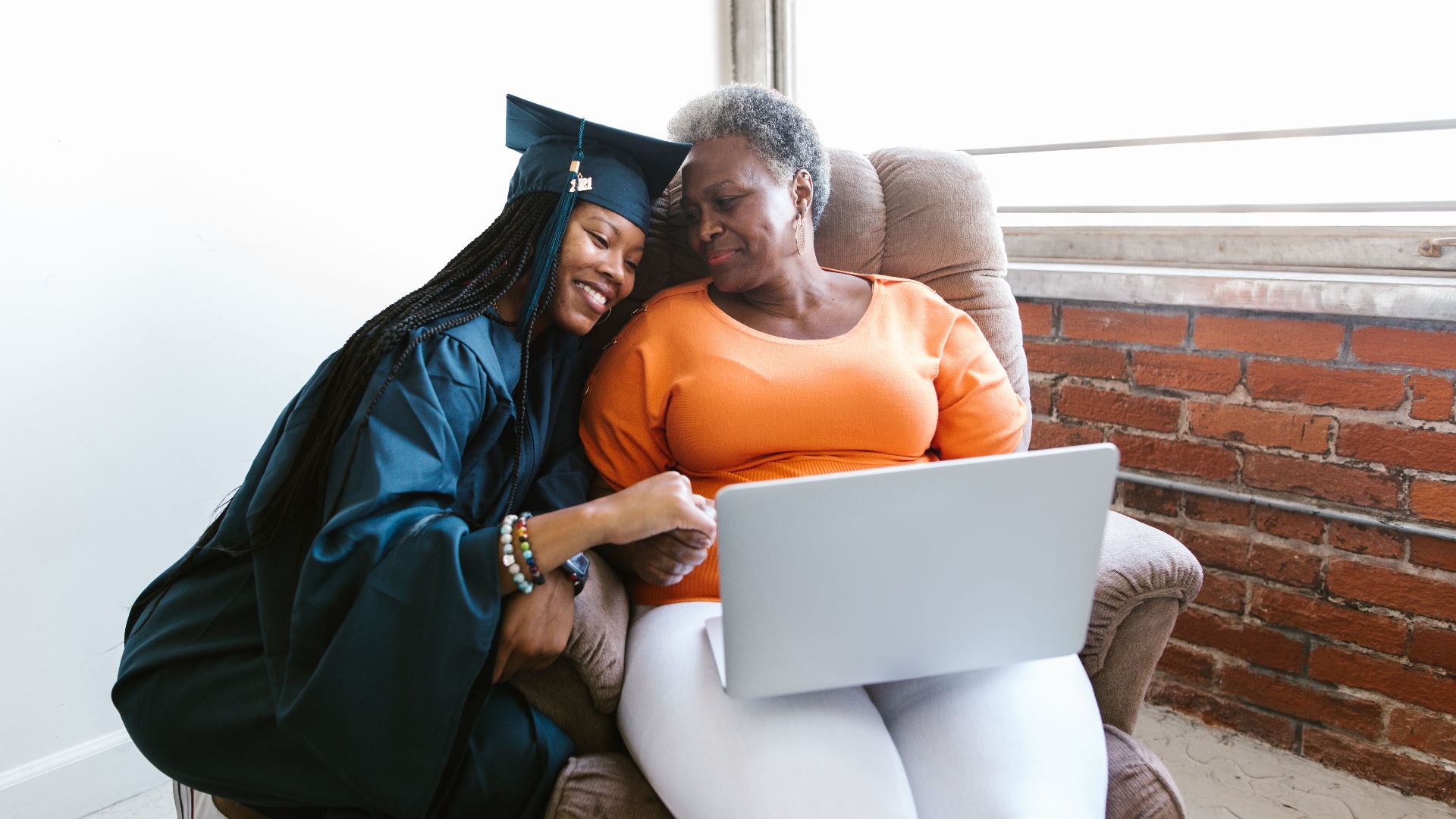 A joyful moment between a mother and daughter during a virtual graduation ceremony, symbolizing achievement and love.