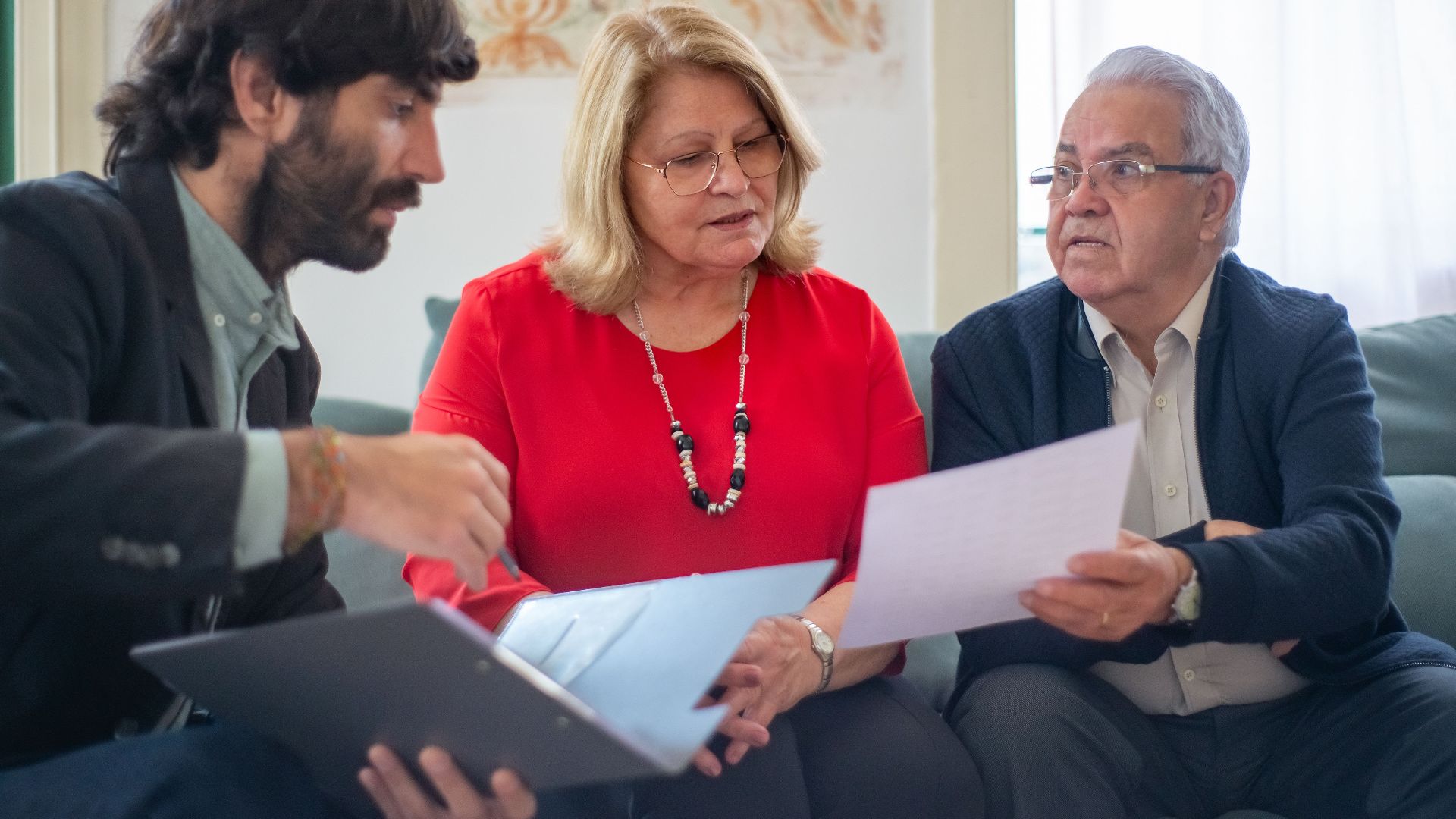 Senior couple consulting with a professional advisor, discussing documents indoors.