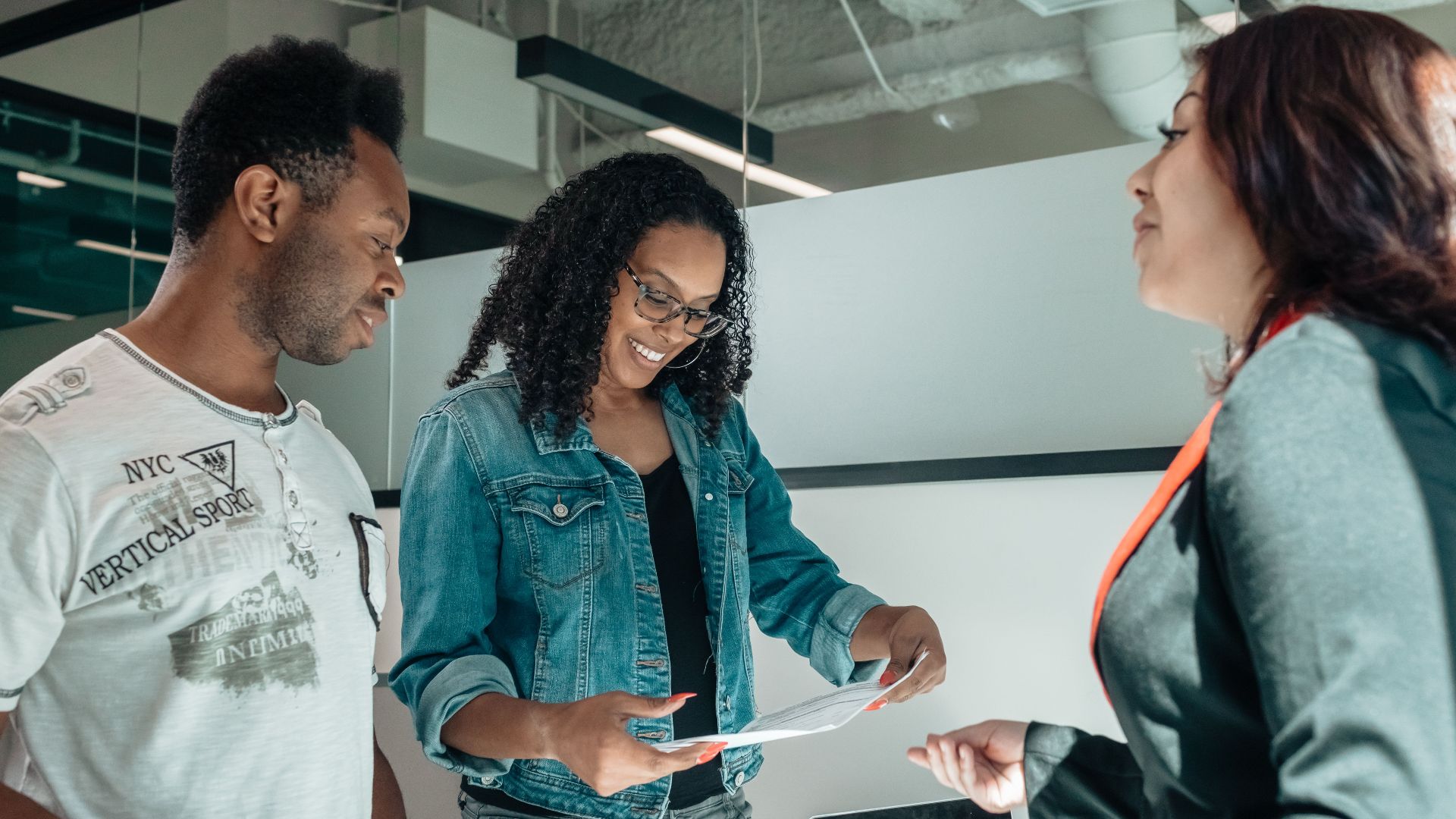 Three adults engaging in a business discussion in a bright, modern office setting.