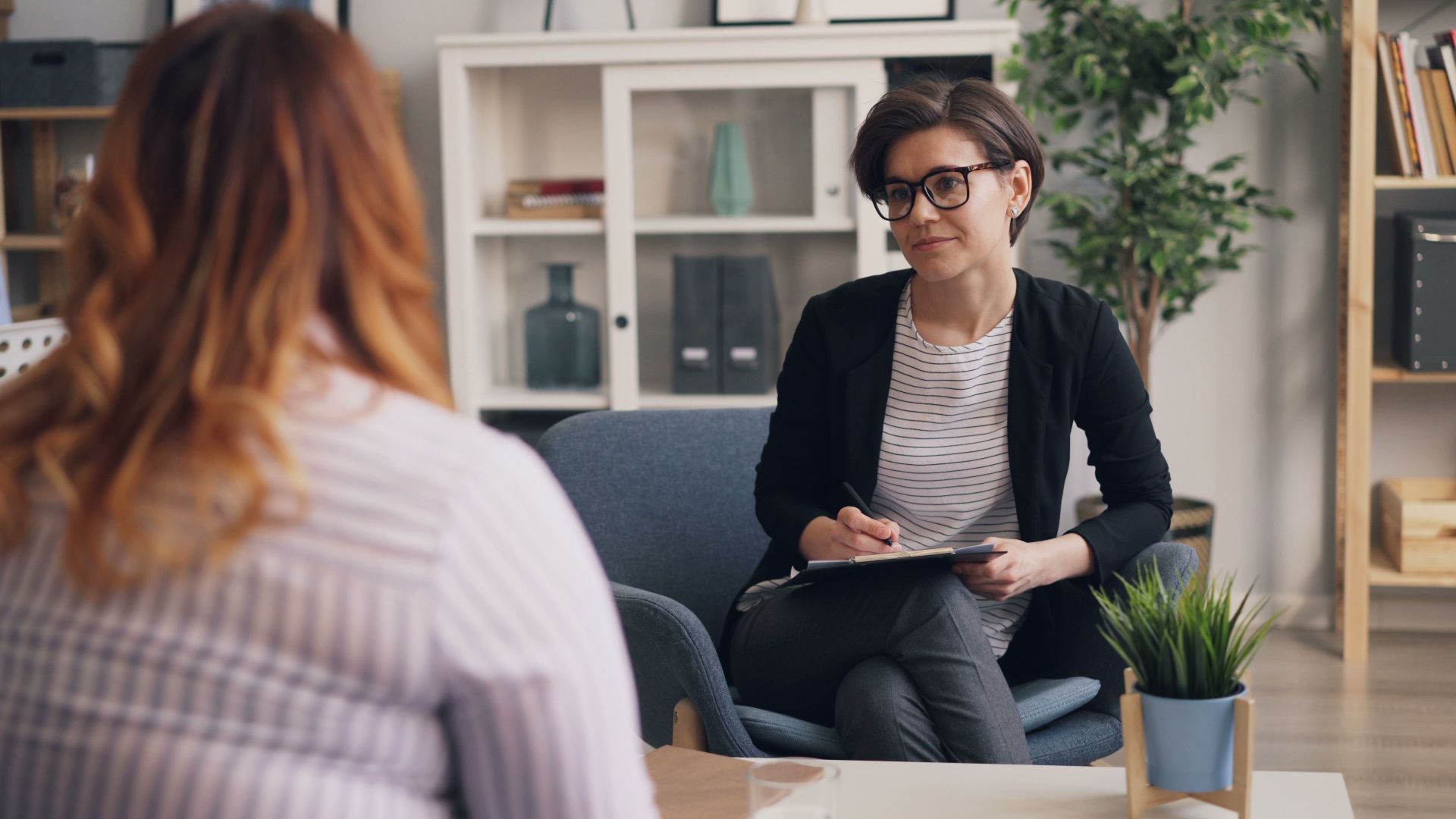 A therapist and patient having a counseling session in a modern office sitting area.