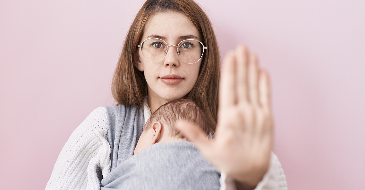 Young caucasian woman holding and carrying baby on a sling