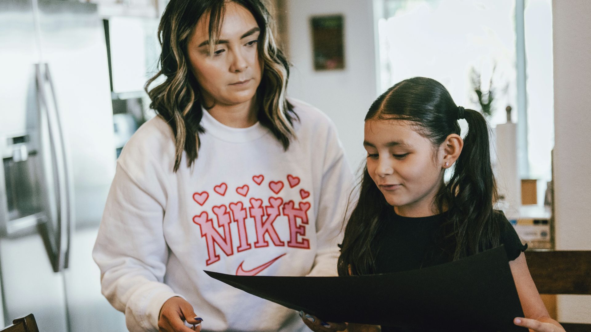 a woman standing next to a little girl in a kitchen
