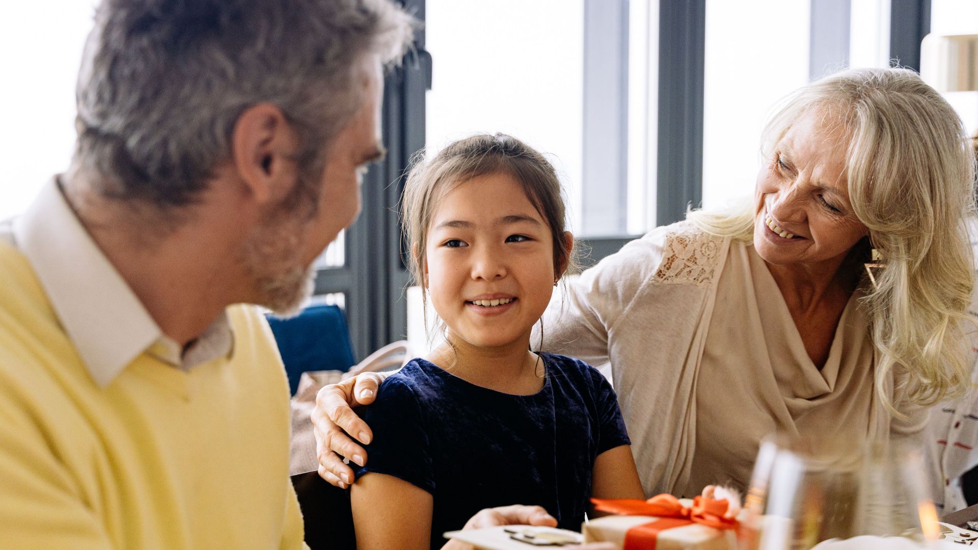 Grandparents and granddaughter sharing a joyful family moment indoors.