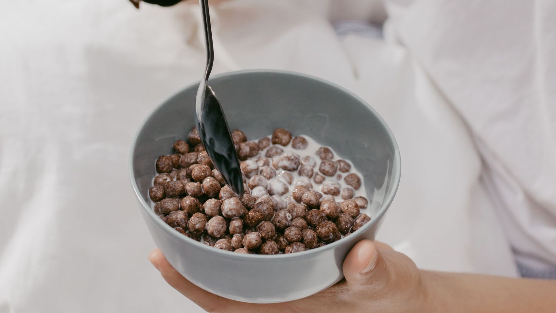 A young man enjoys chocolate cereal in a cozy indoor setting.