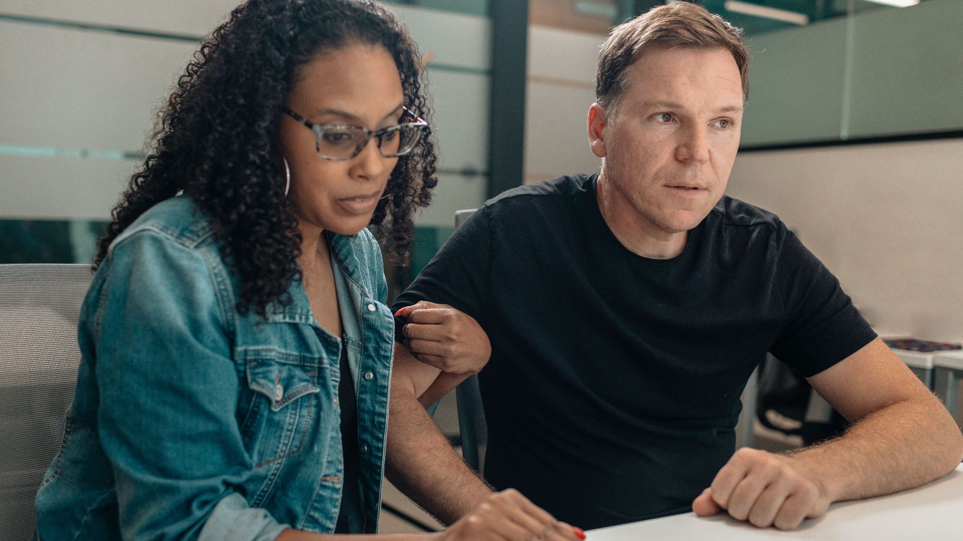 A couple closely examining paperwork in a modern office space. Focused and serious mood.