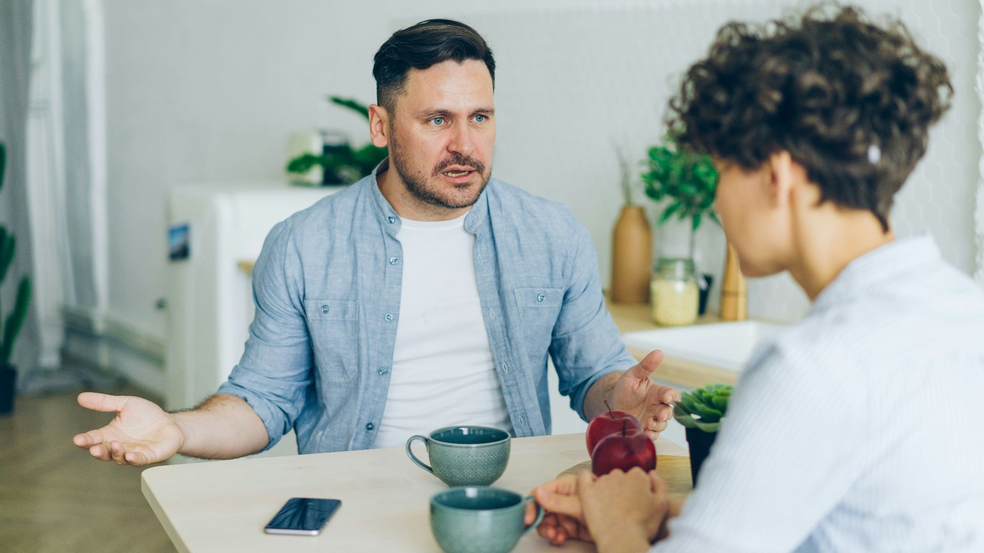 a man sitting at a table talking to a woman