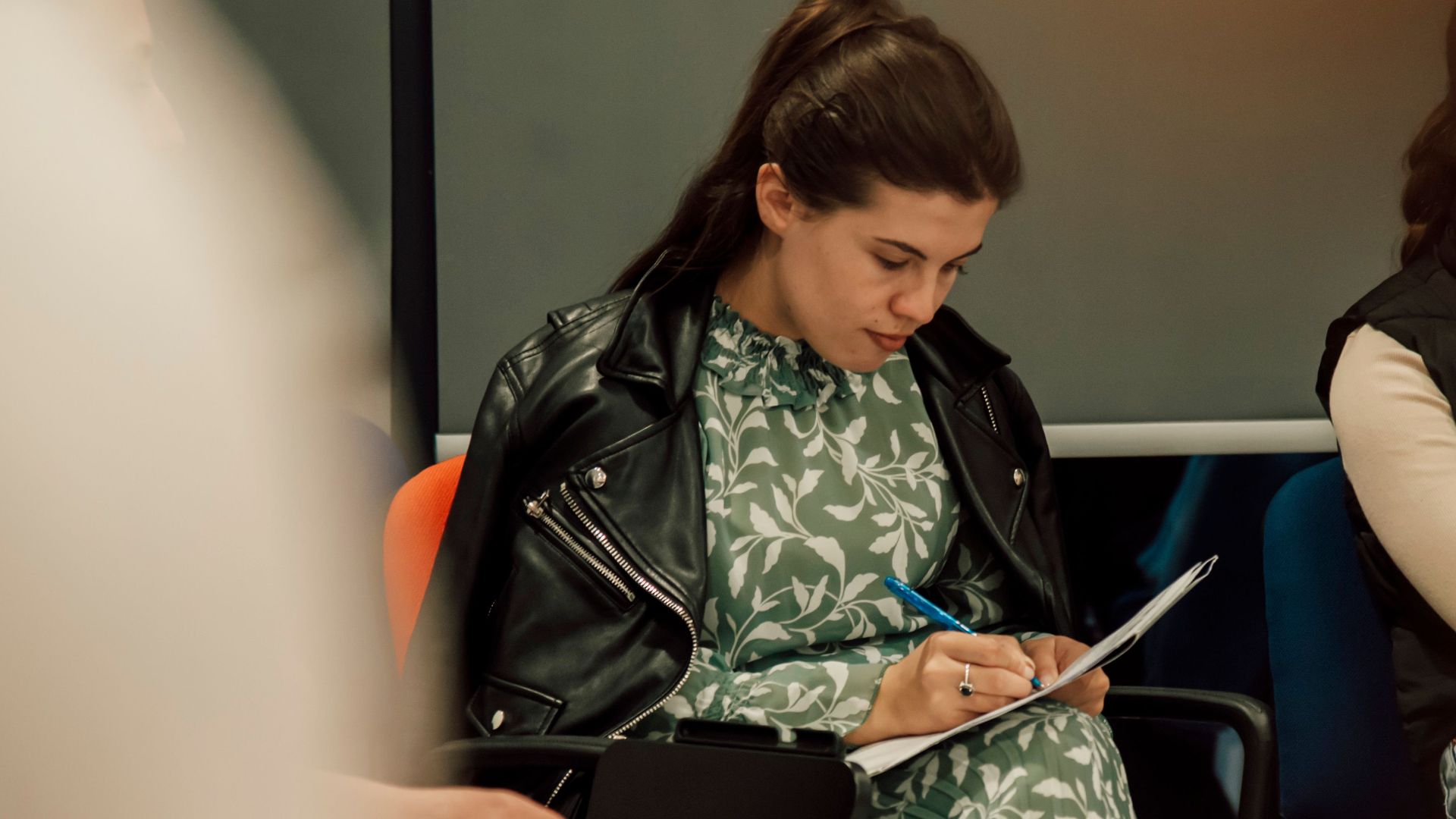 Women taking notes during a meeting indoors, highlighting professional focus.