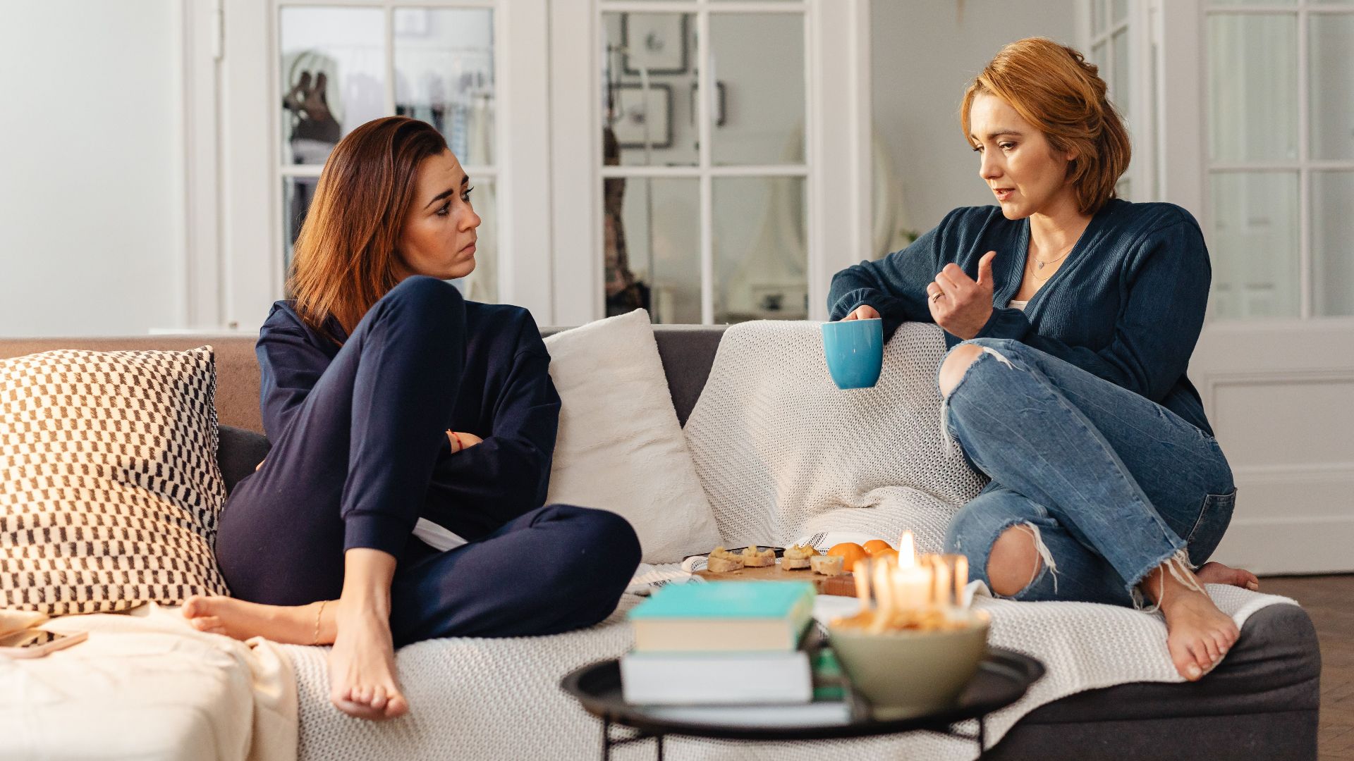 Two women having a heartfelt conversation, enjoying a cozy moment in a modern living room.