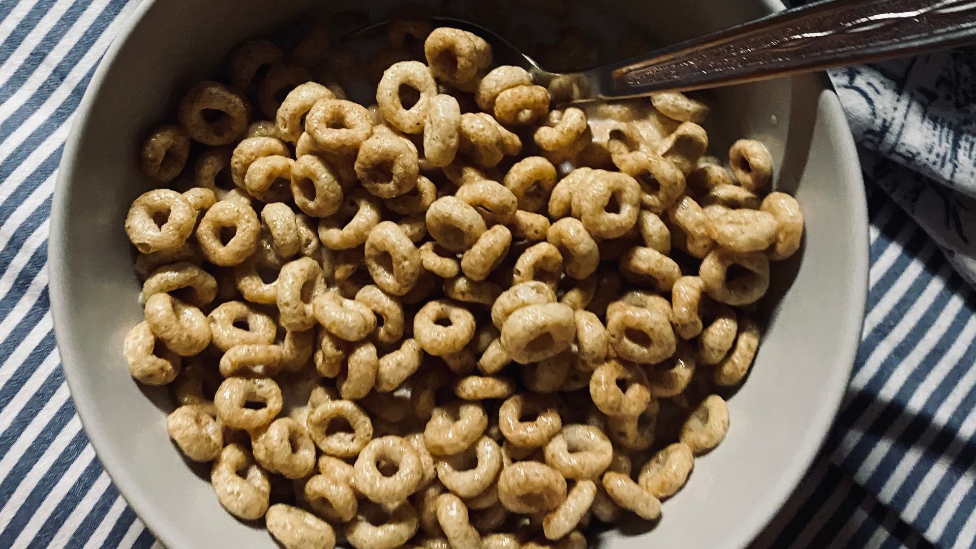 A bowl of nutritious cereal rings served on a striped fabric background.