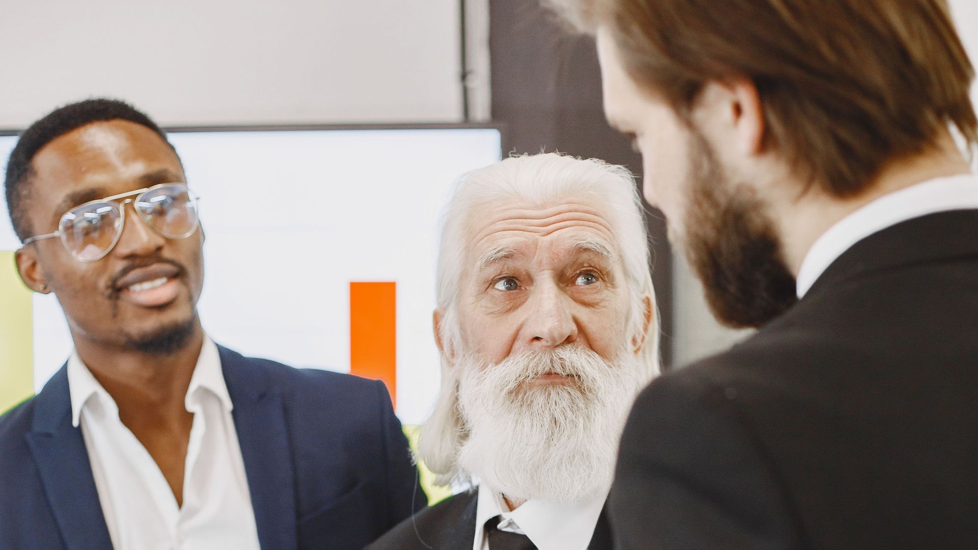 A diverse group of businessmen engaged in a meeting, discussing reports in an office setting.