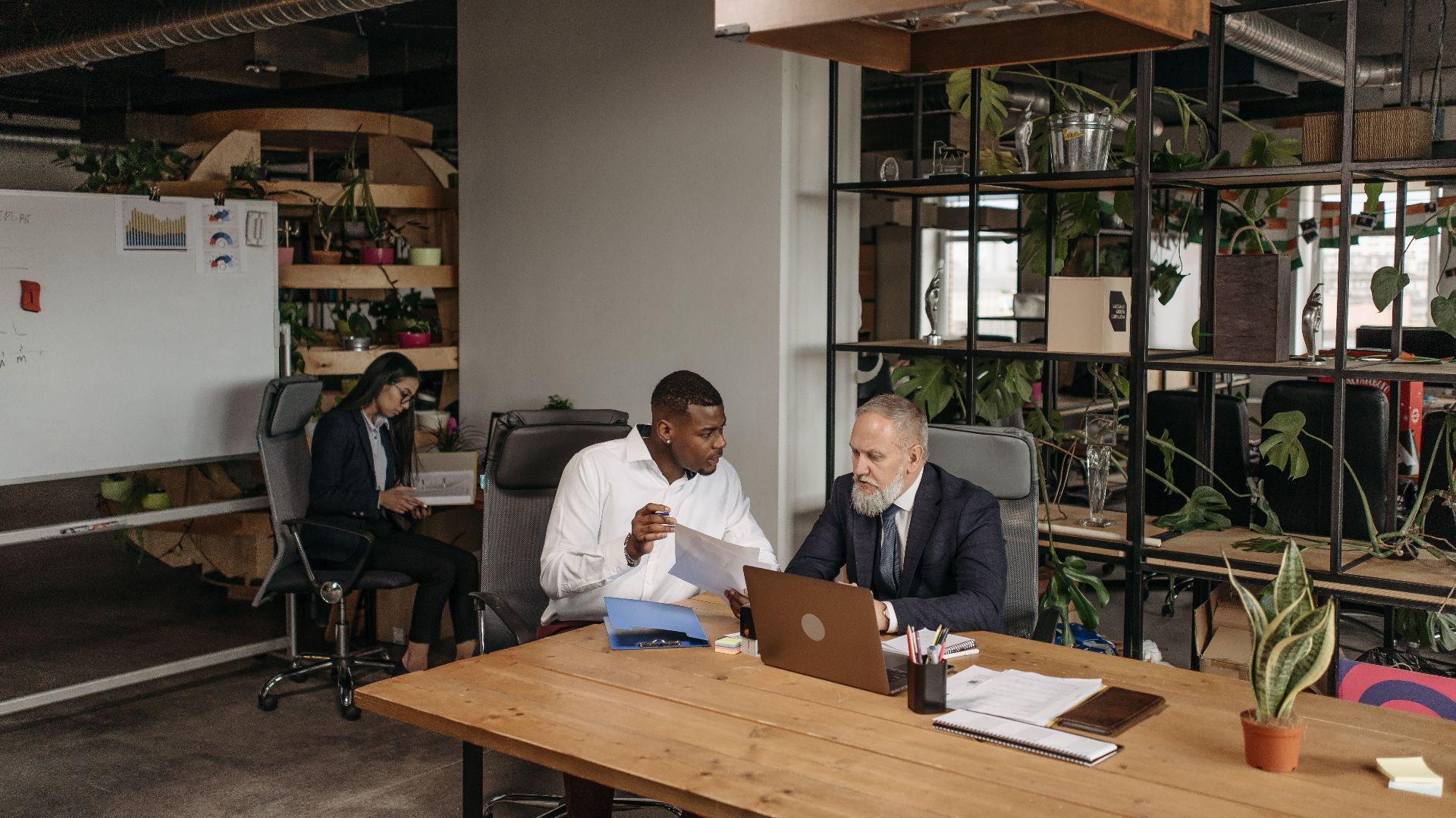 A diverse group of professionals discussing work documents in a contemporary office setting.