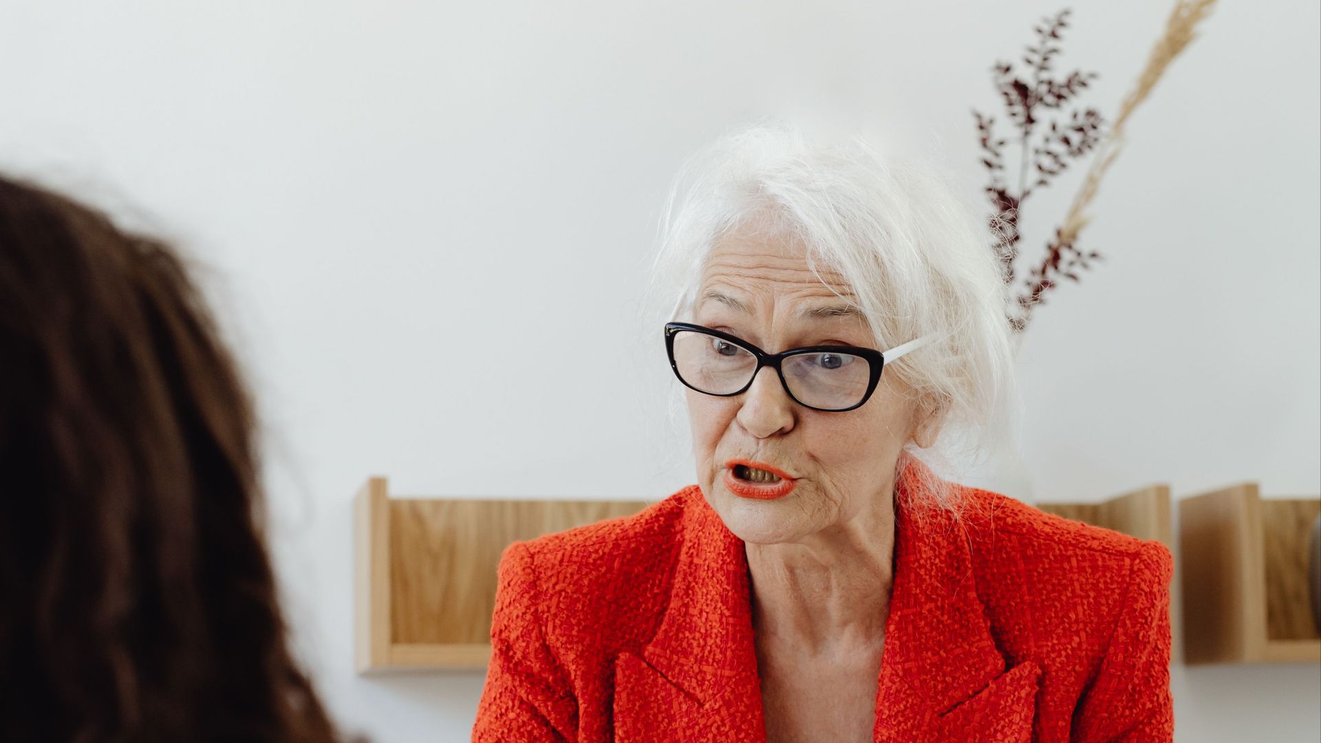 Senior businesswoman in a red blazer engaging in a professional meeting at the office.