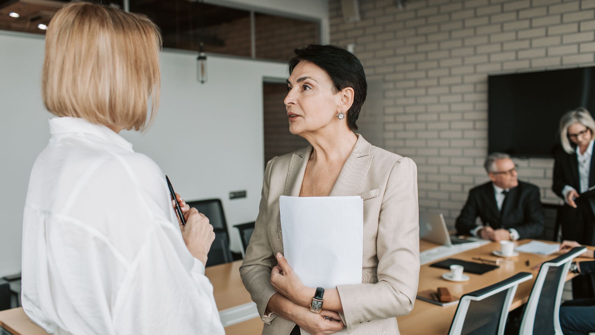 Two businesswomen engage in a conversation during a professional meeting in a modern office.
