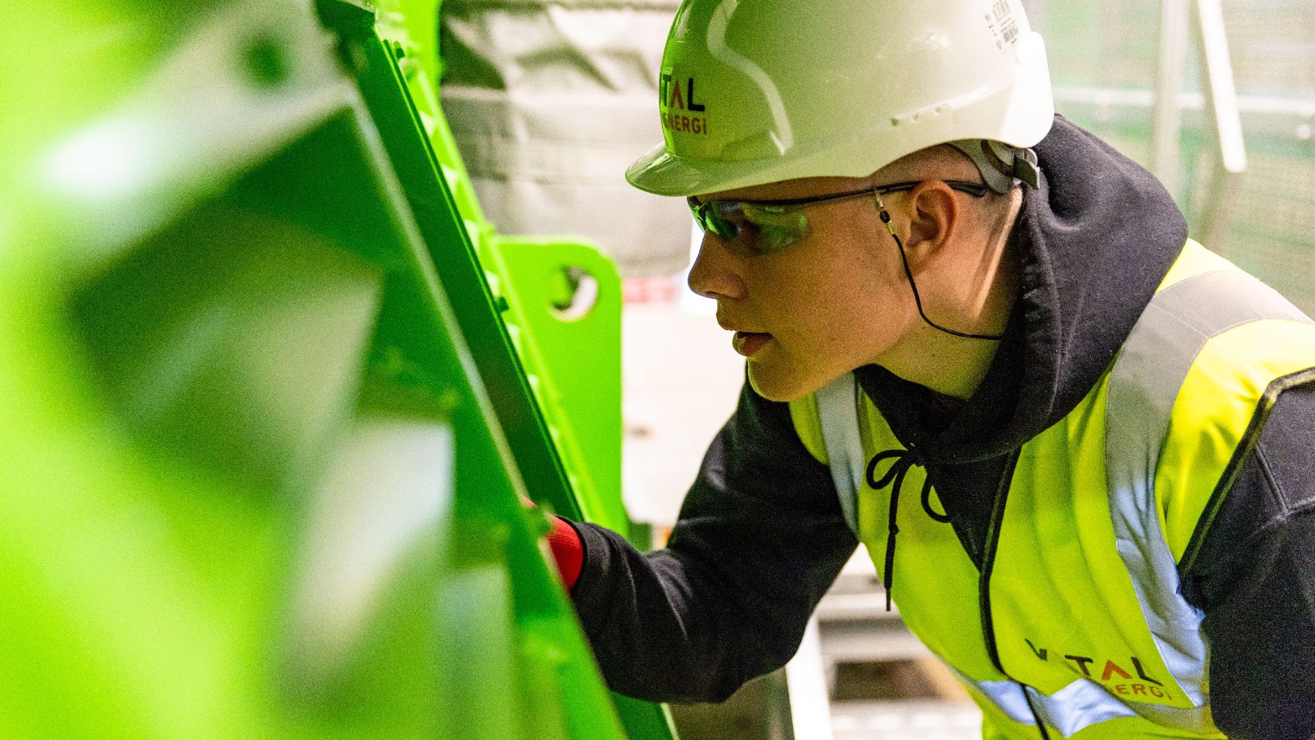 Safety-conscious factory worker inspects machinery for quality control in industrial setting.
