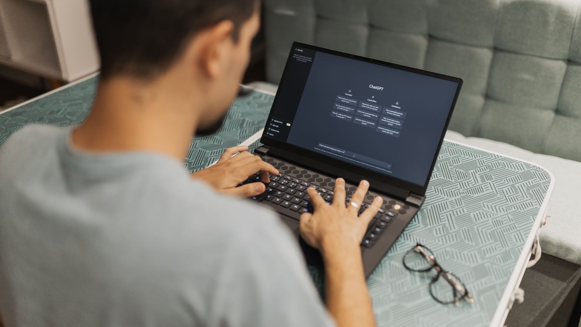 A man working on a laptop displaying ChatGPT's interface in an indoor setting.