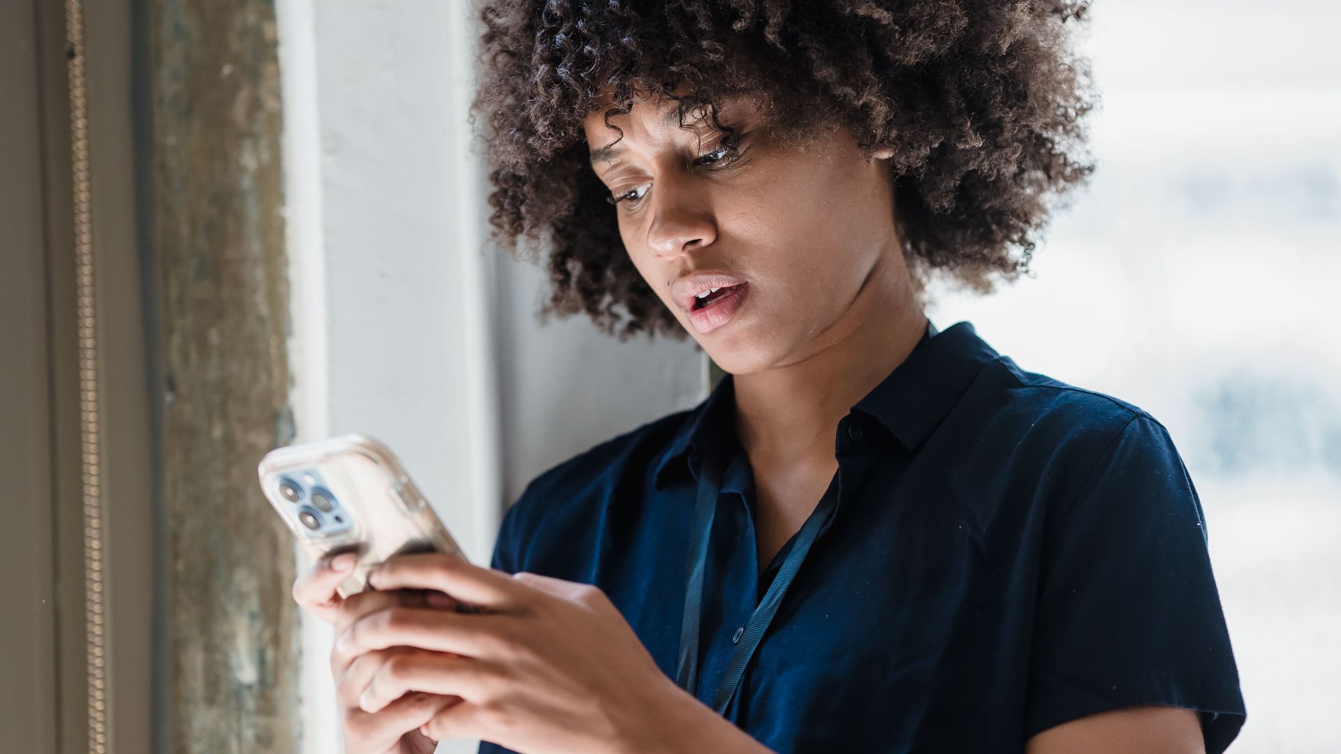 Young woman engaging with smartphone in modern office setting.