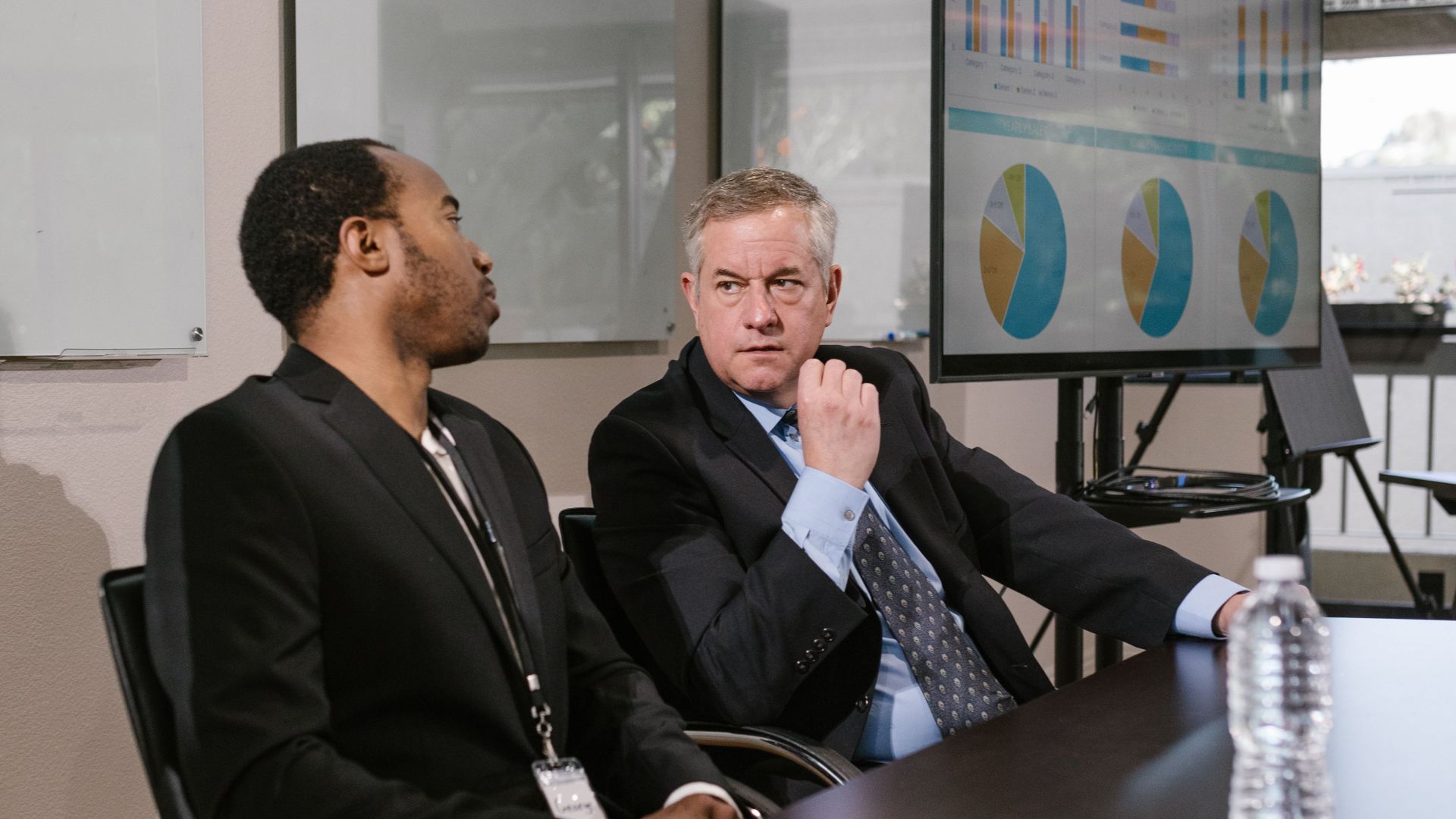 Two men in business attire engage in a professional discussion in a modern office.