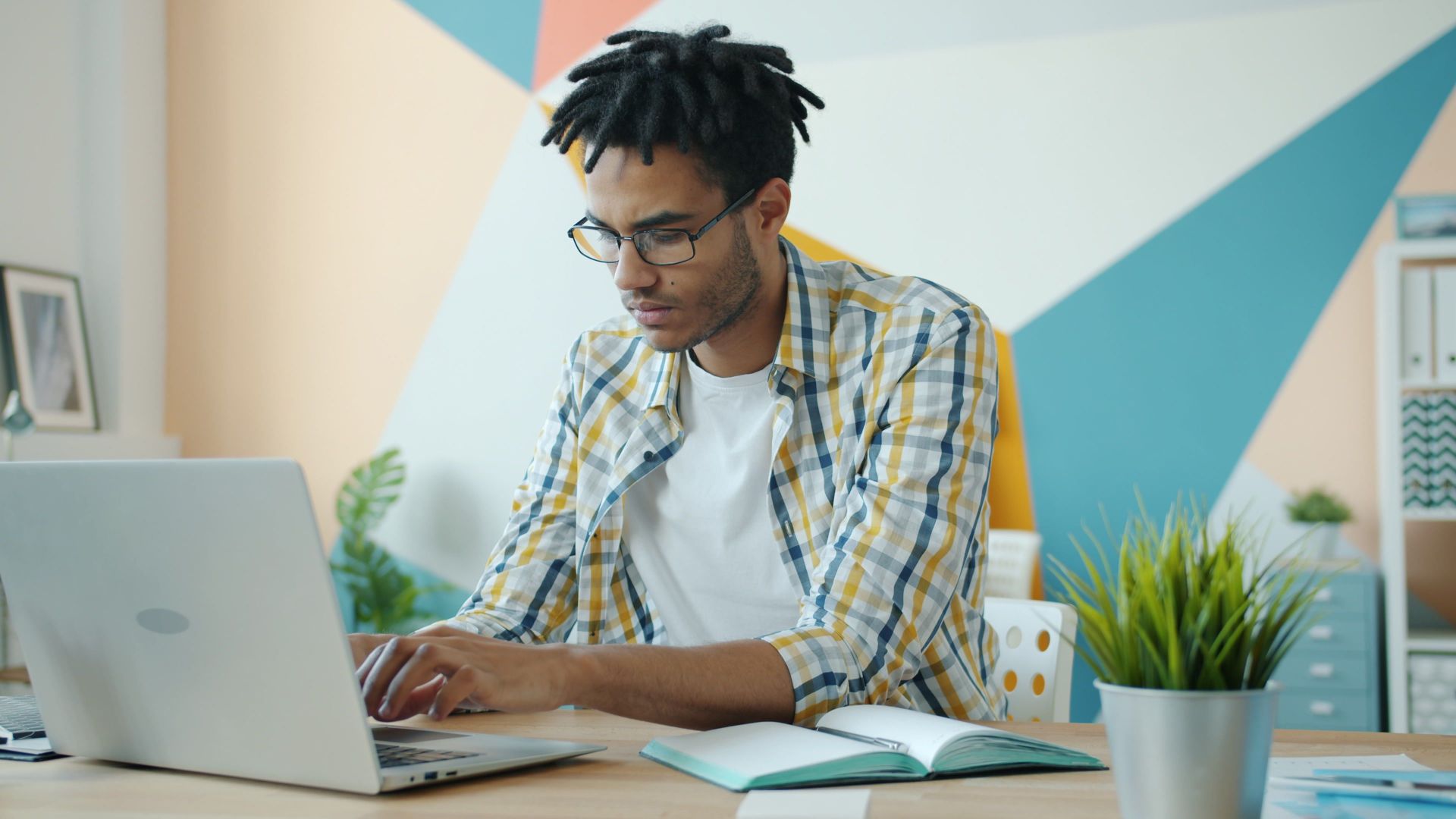 Young professional in modern office working on a laptop, focused and productive.