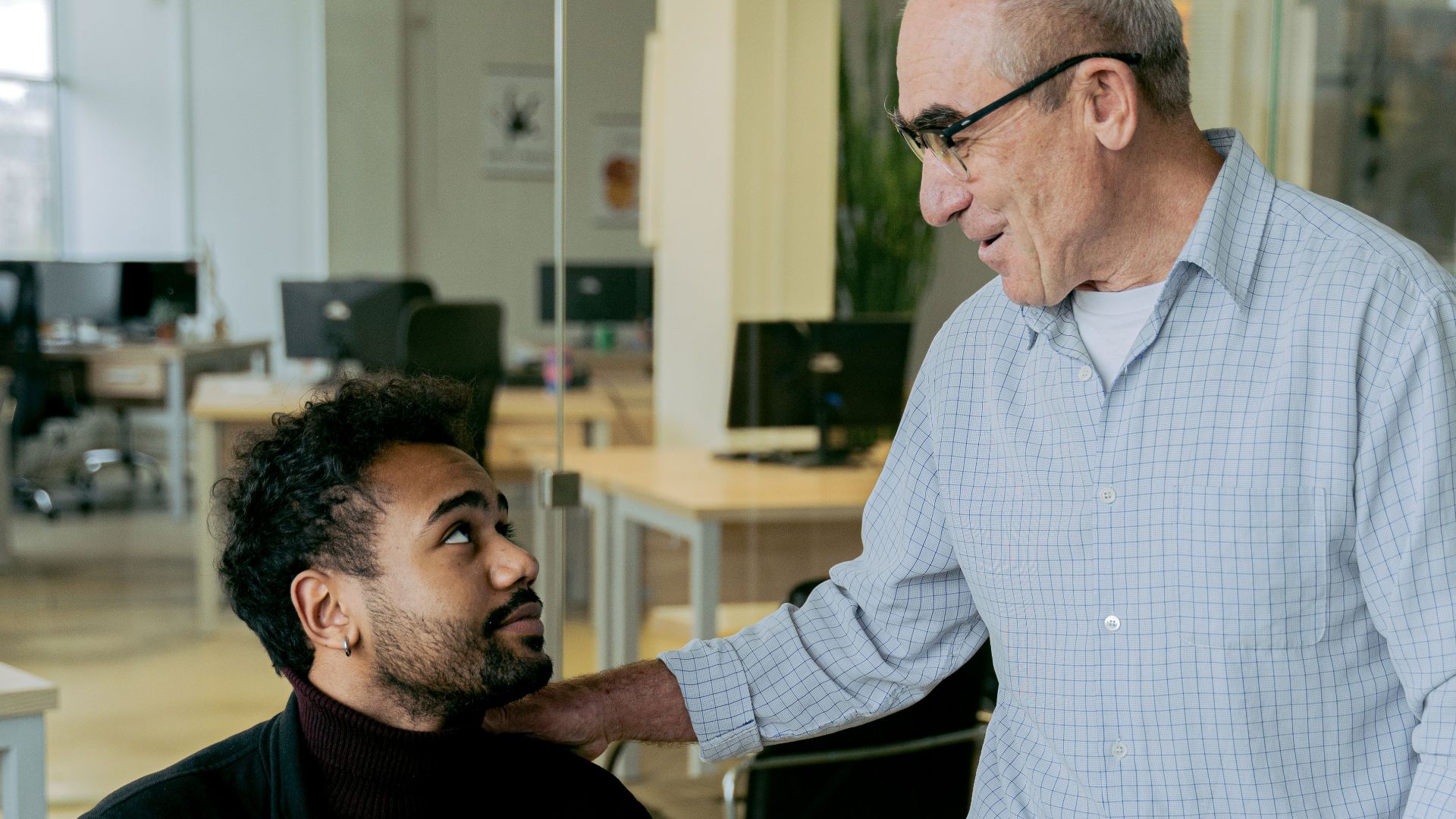 Two colleagues discussing work in a bright, modern office setting.