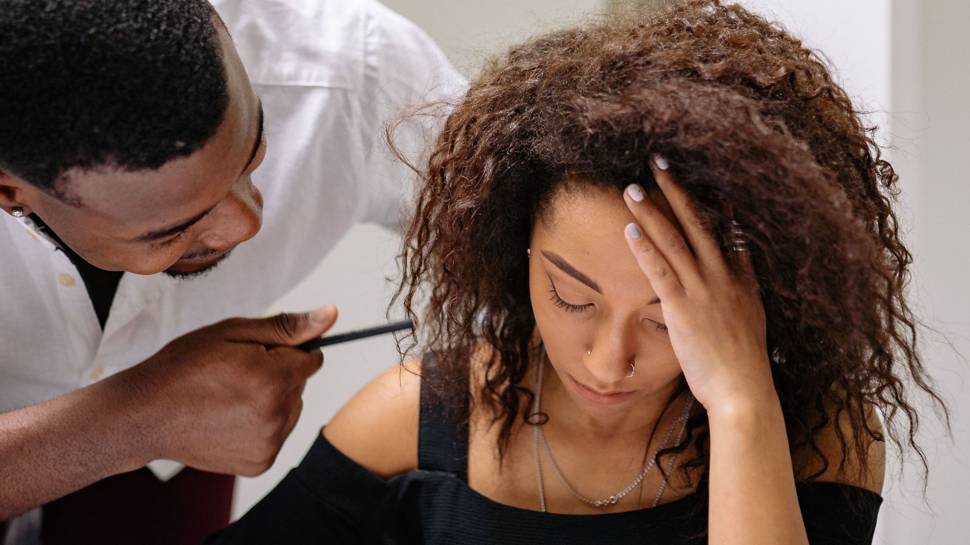 An adult man scolds a distressed woman in an office setting, illustrating workplace tension.