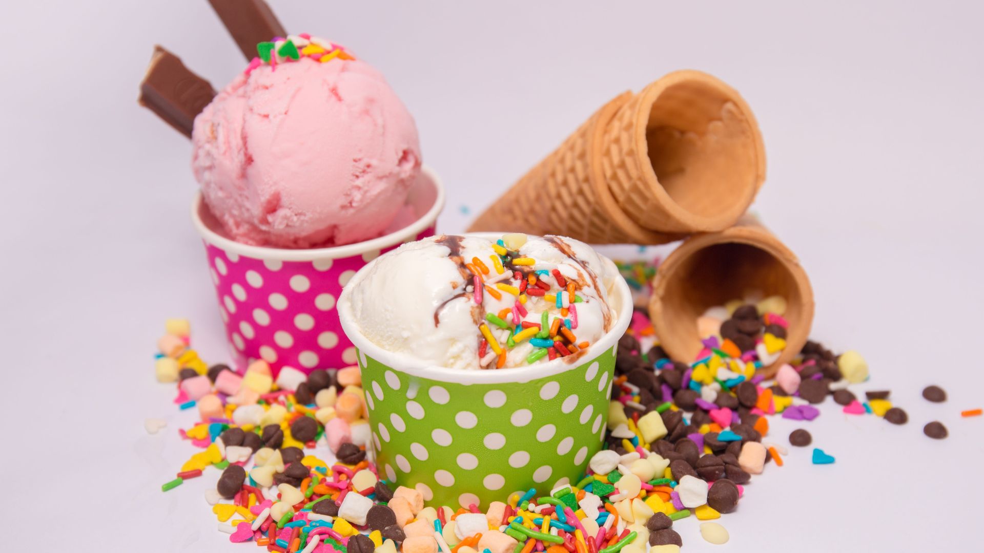 Delicious ice cream in vibrant cups with scattered sprinkles and waffle cones.