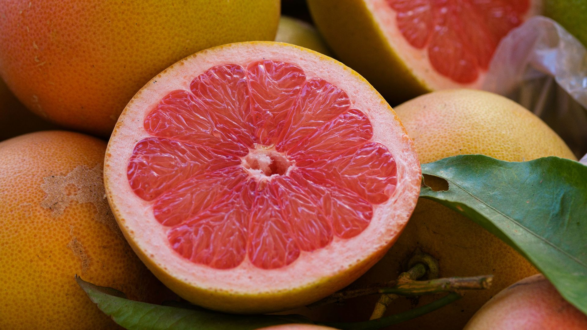 a pile of grapefruits with one cut in half