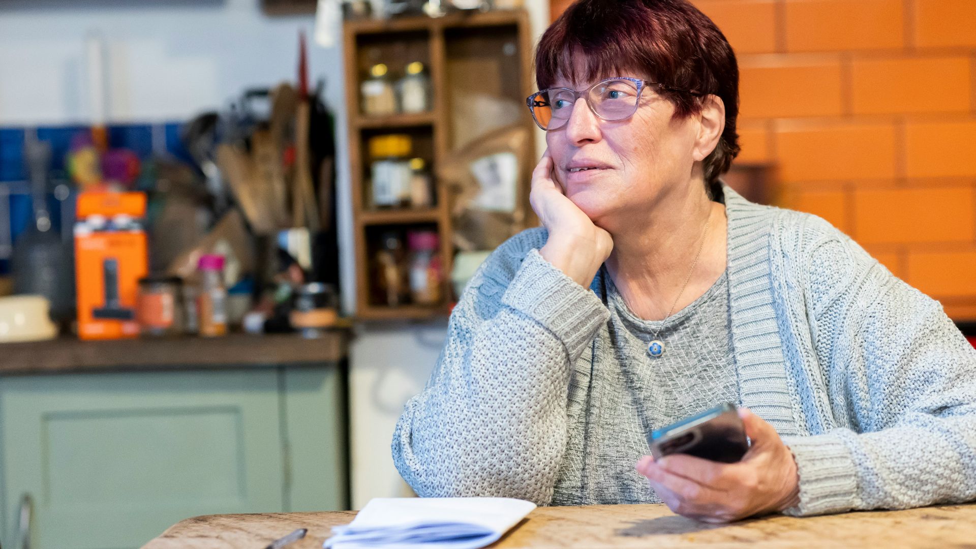 a woman sitting at a table with a cell phone