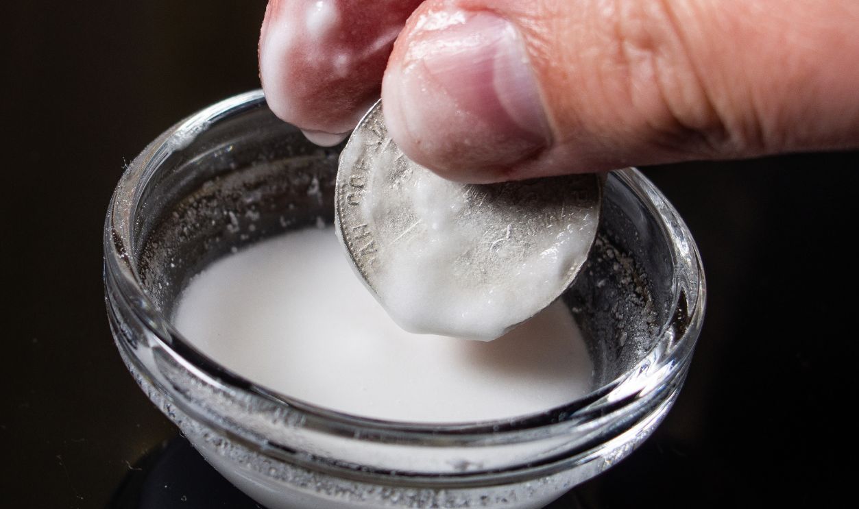 man cleans antique collectible silver coins in a special cleaning solution for coins