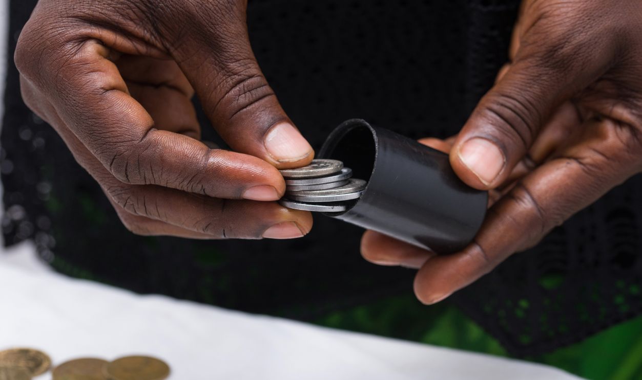 female hand putting silver coins in a box.