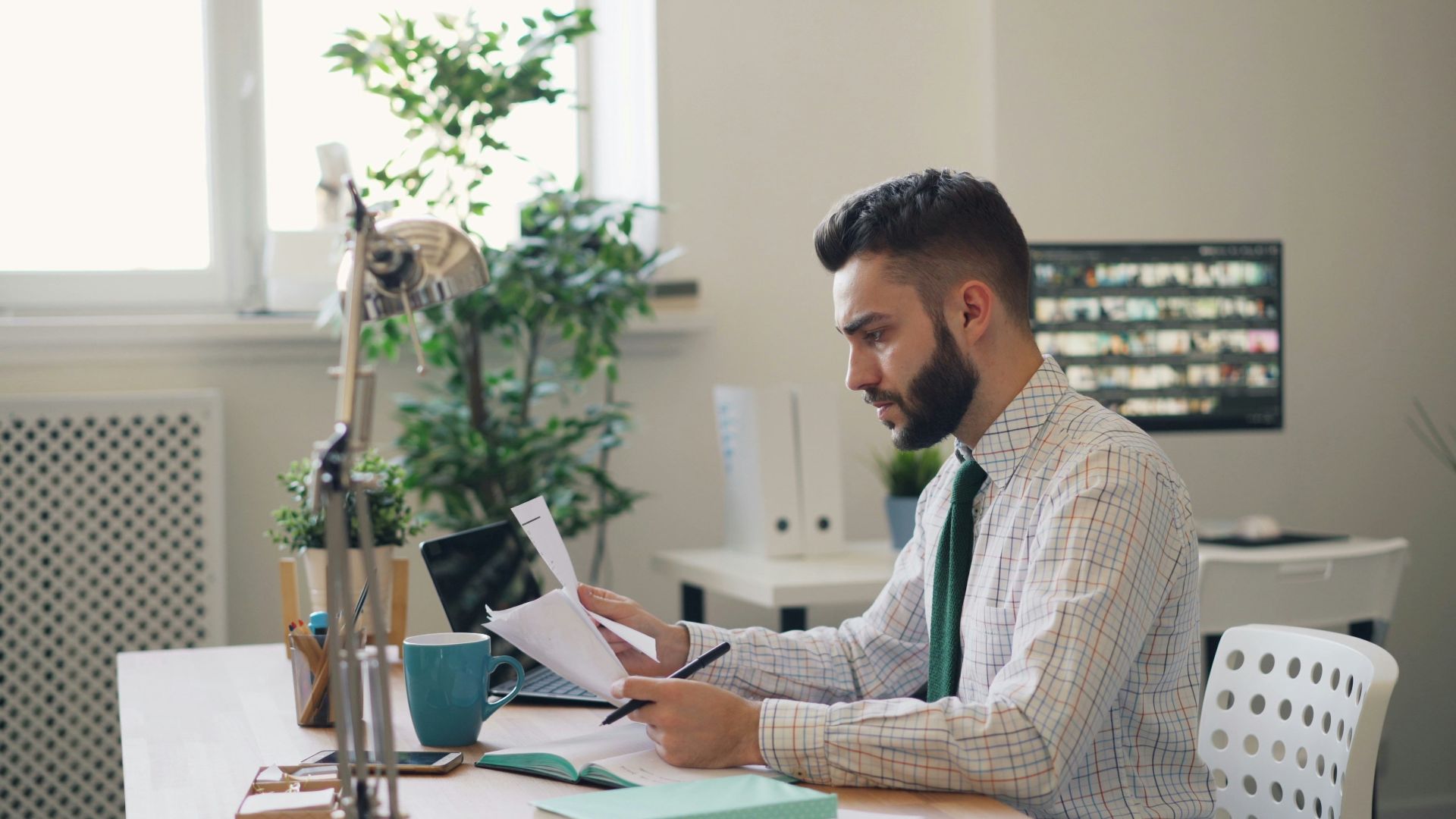 a man sitting at a desk with a laptop and papers