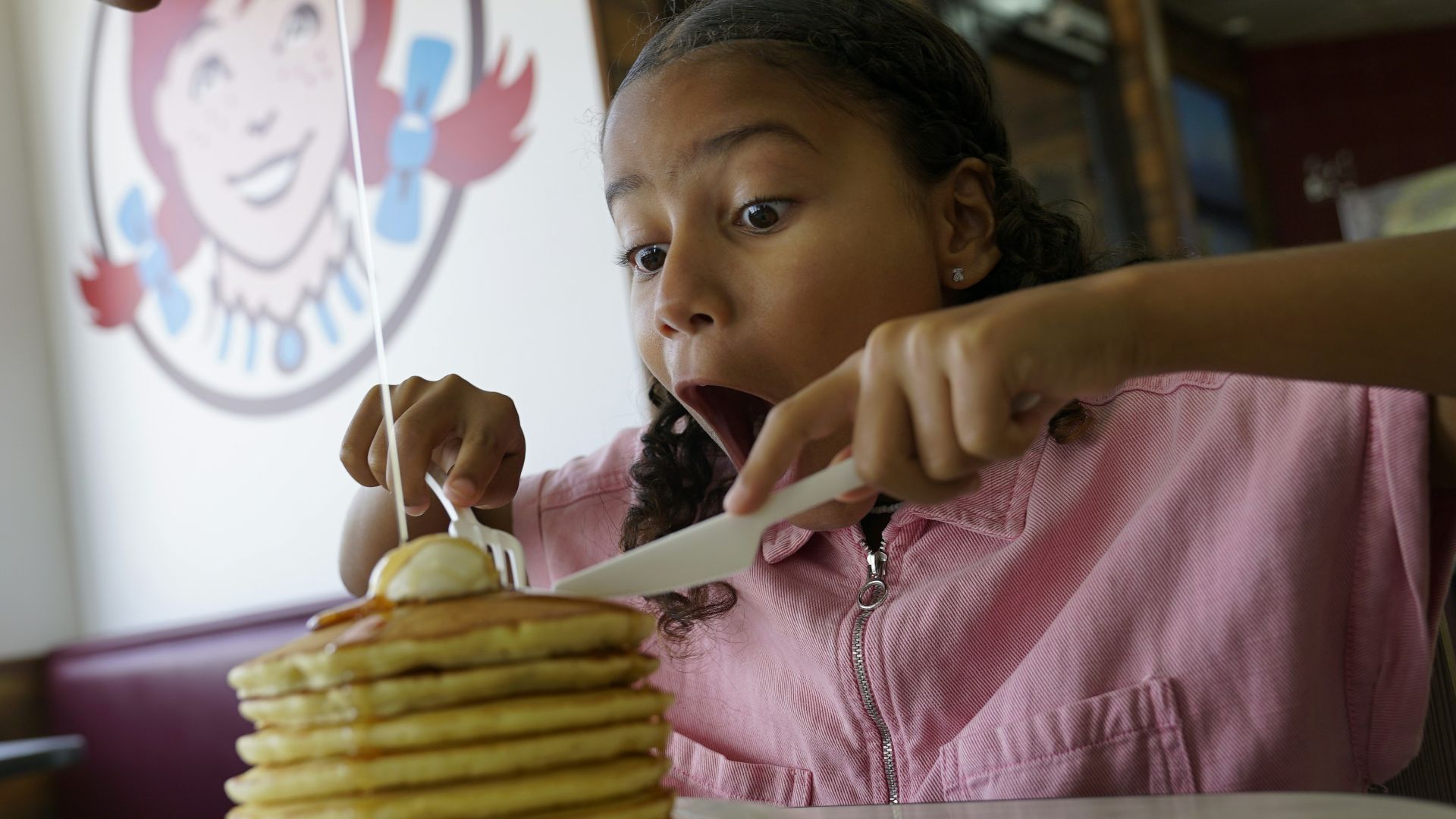 Young girl eating a large stack of pancakes
