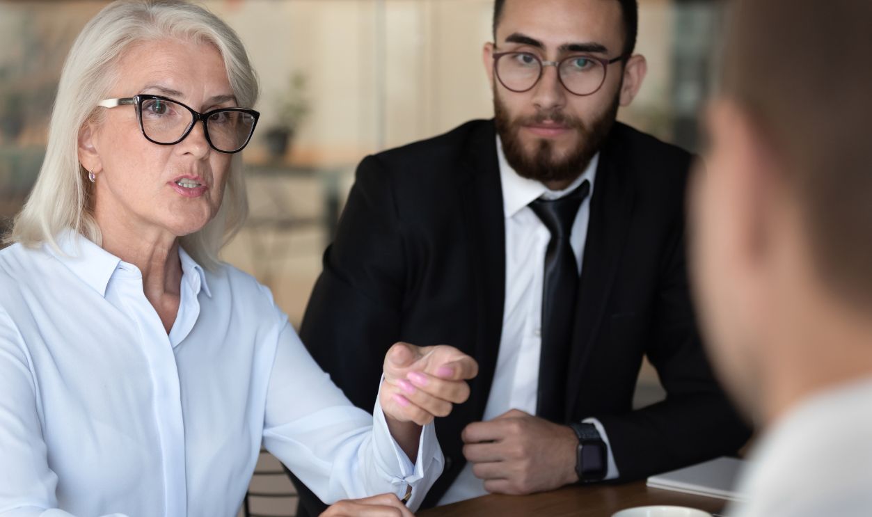 Negotiations lead by middle-aged boss talking with client diverse business people gathered together at boardroom, job interview process european and arabian HR managers interweaving applicant concept