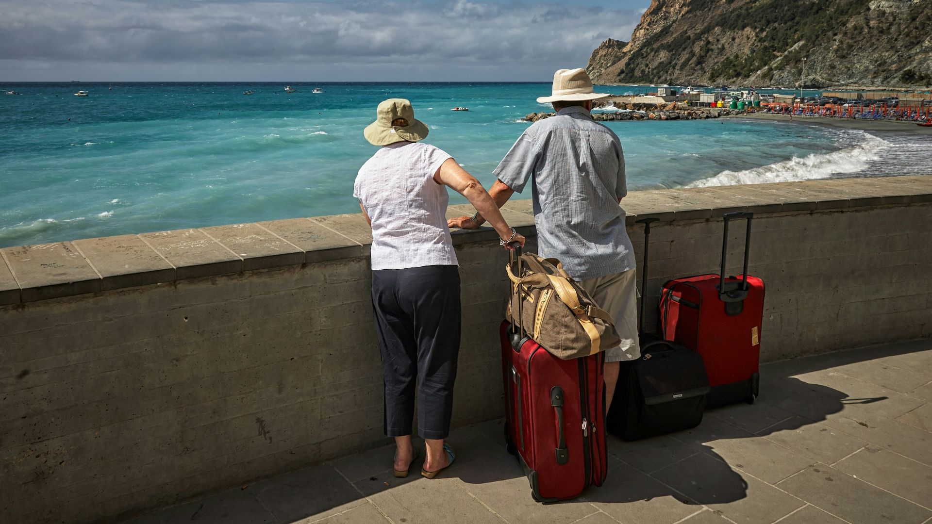 man and woman standing beside concrete seawall looking at beach