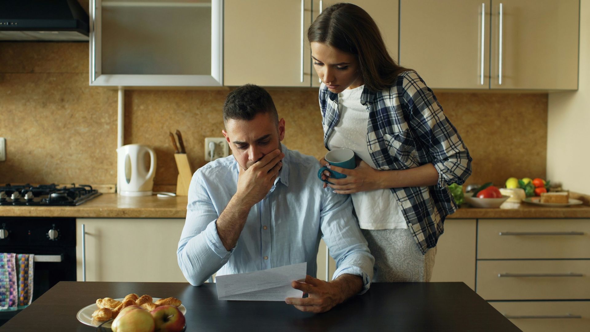 Couple looking stressed over bills at kitchen table