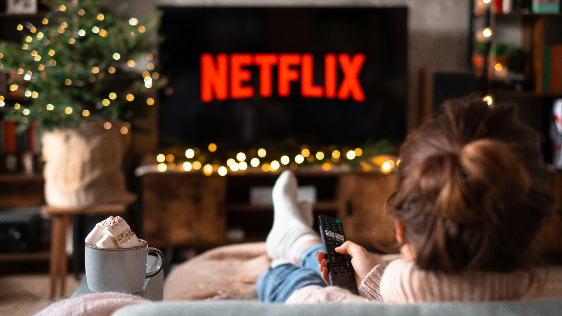 a little girl sitting on a couch watching tv