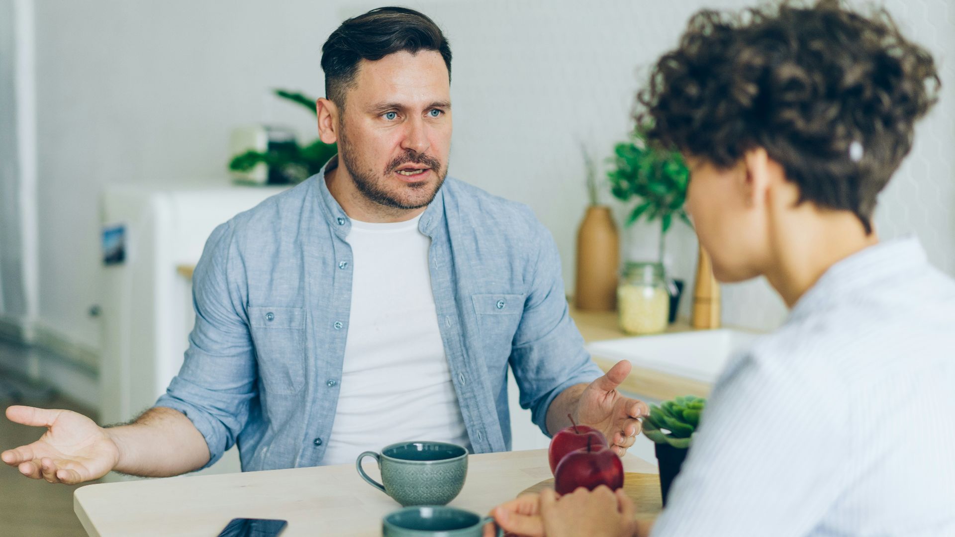 a man sitting at a table talking to a woman