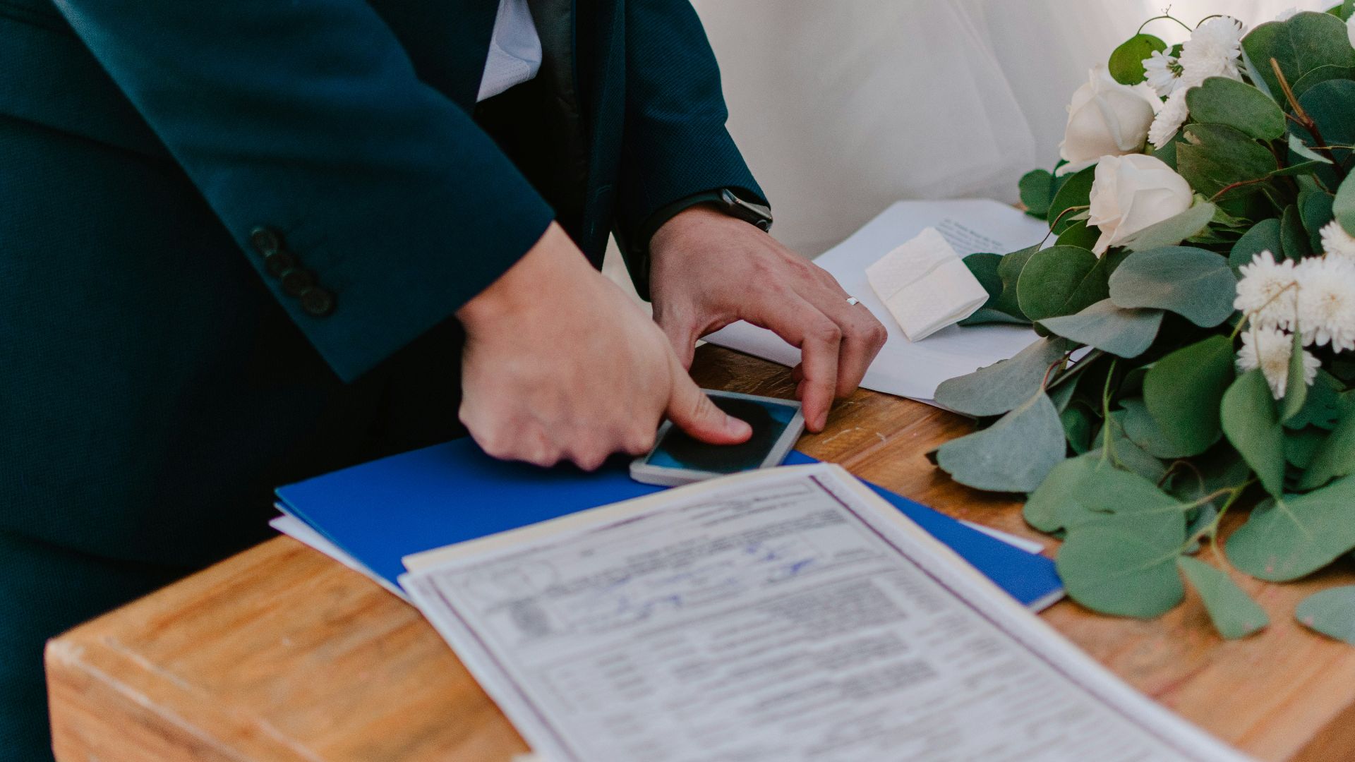 Couple signing marriage certificate with bouquet nearby flowers nearby flowers