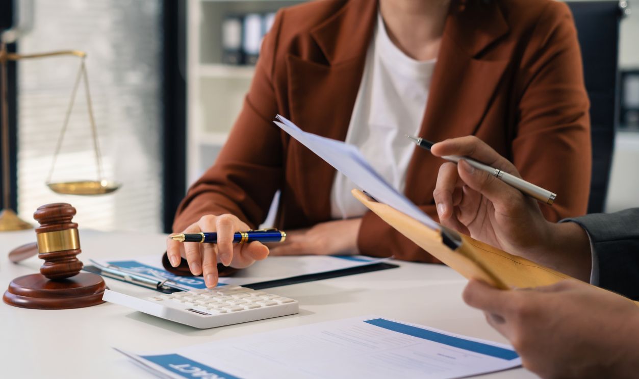 Lawyer or accounting department writes a note and uses a calculator to calculate expenses - income. at office lawyer.