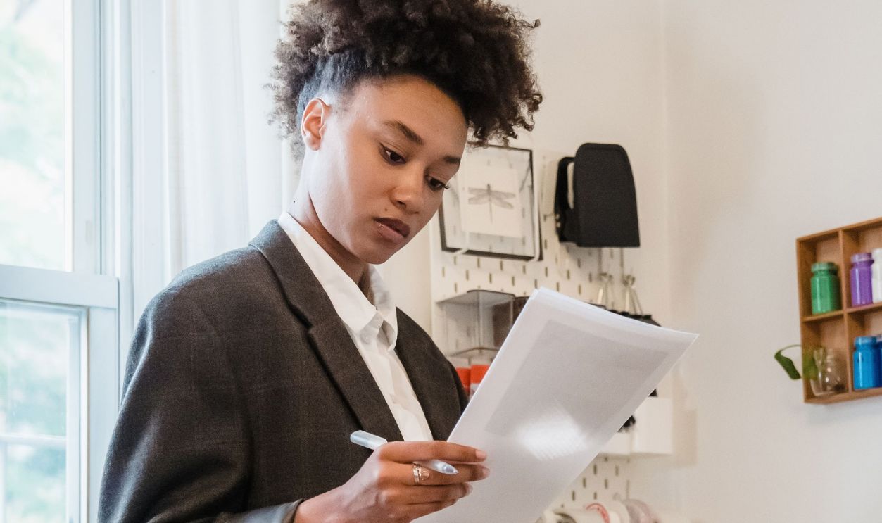 Young woman in home office reviewing documents by the desk