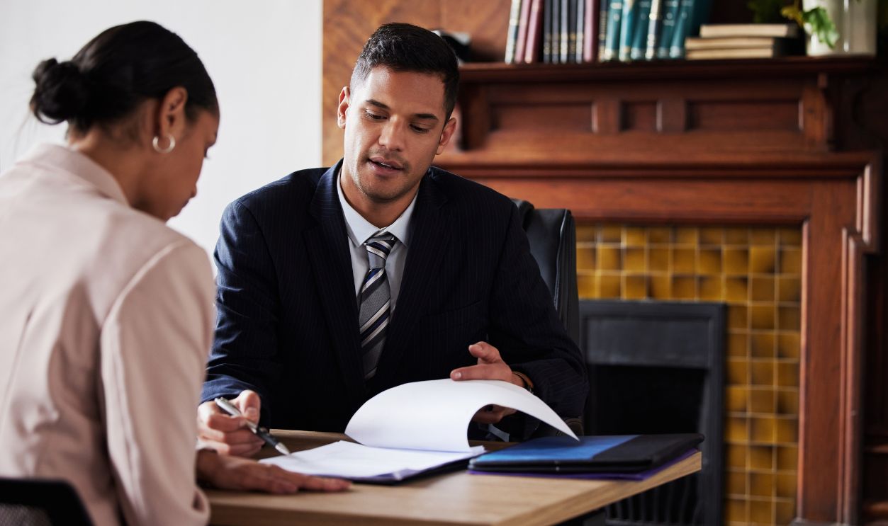 Shutterstock-2272166485, Contract, signing and lawyer consulting a client in his office with legal paperwork or agreement. Signature, approval and businessman in discussion with a woman with a document to sign in workplace.