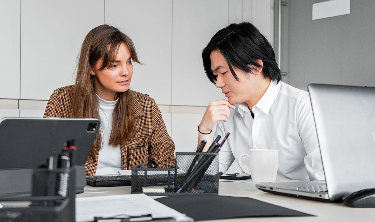 Asian man and Caucasian woman discussing a project in a modern office