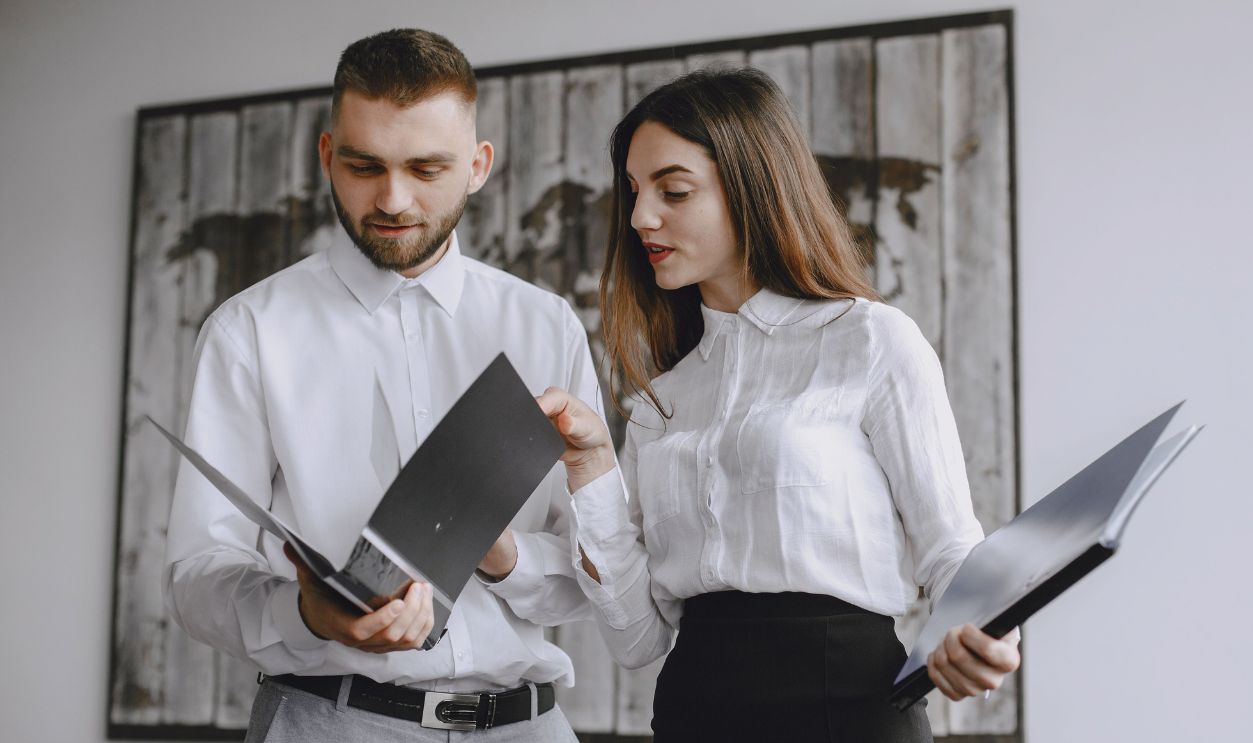 Two colleagues in a modern office reviewing documents