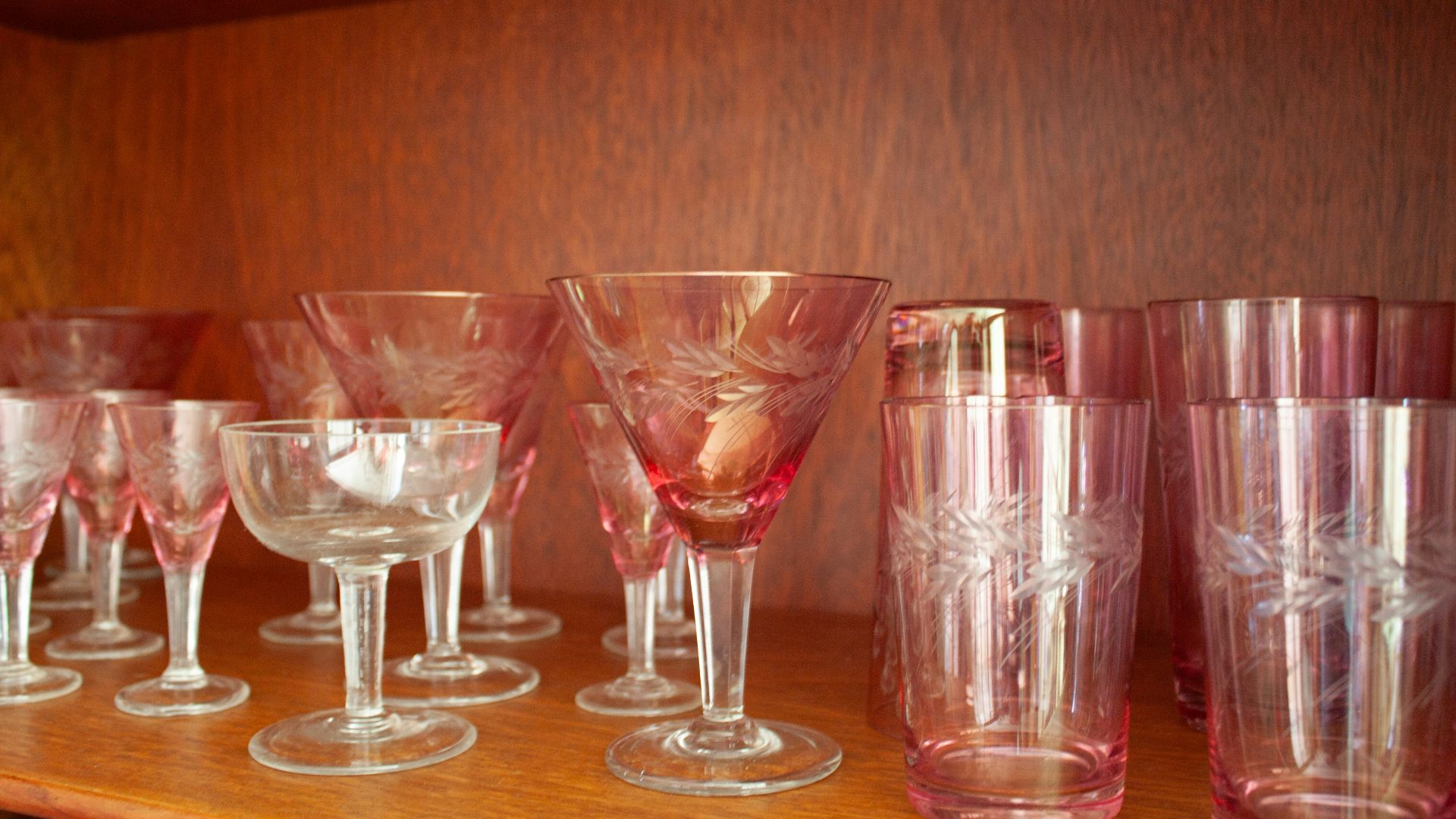 Pink and clear glassware displayed on a wooden shelf