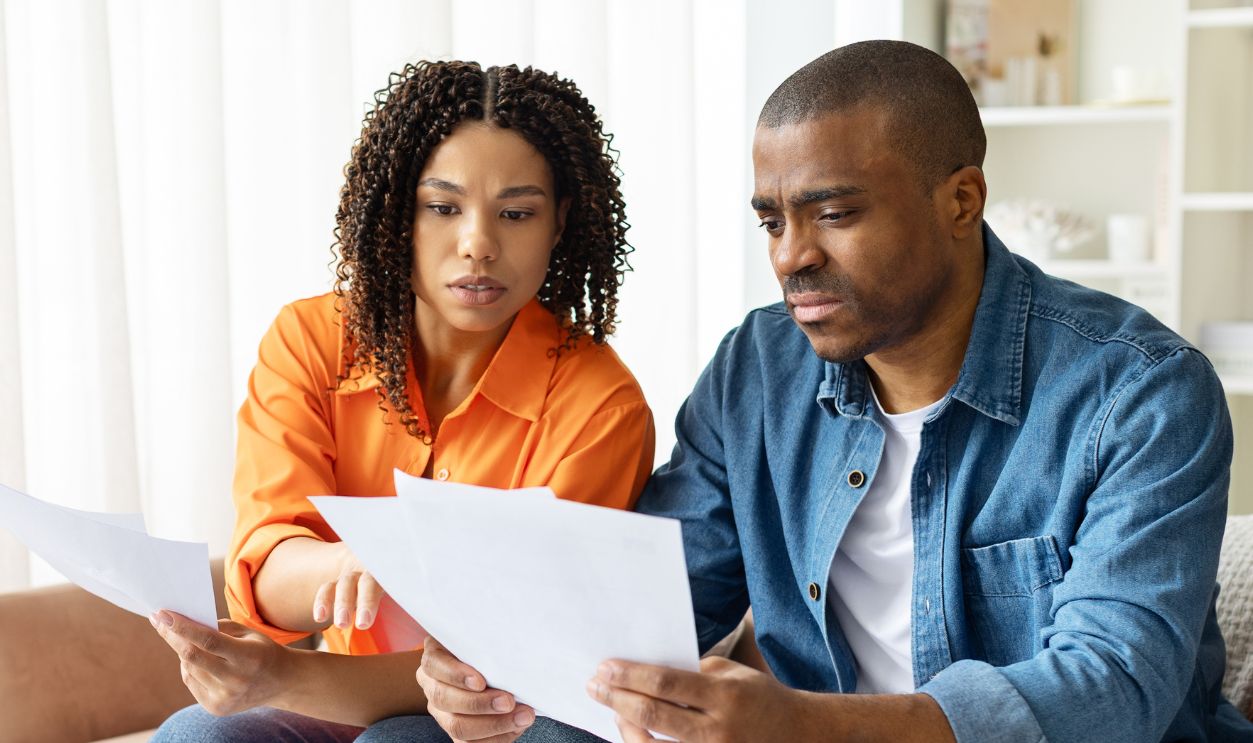 Shutterstock-2682077609, Focused African American couple working on finances at home, reading documents