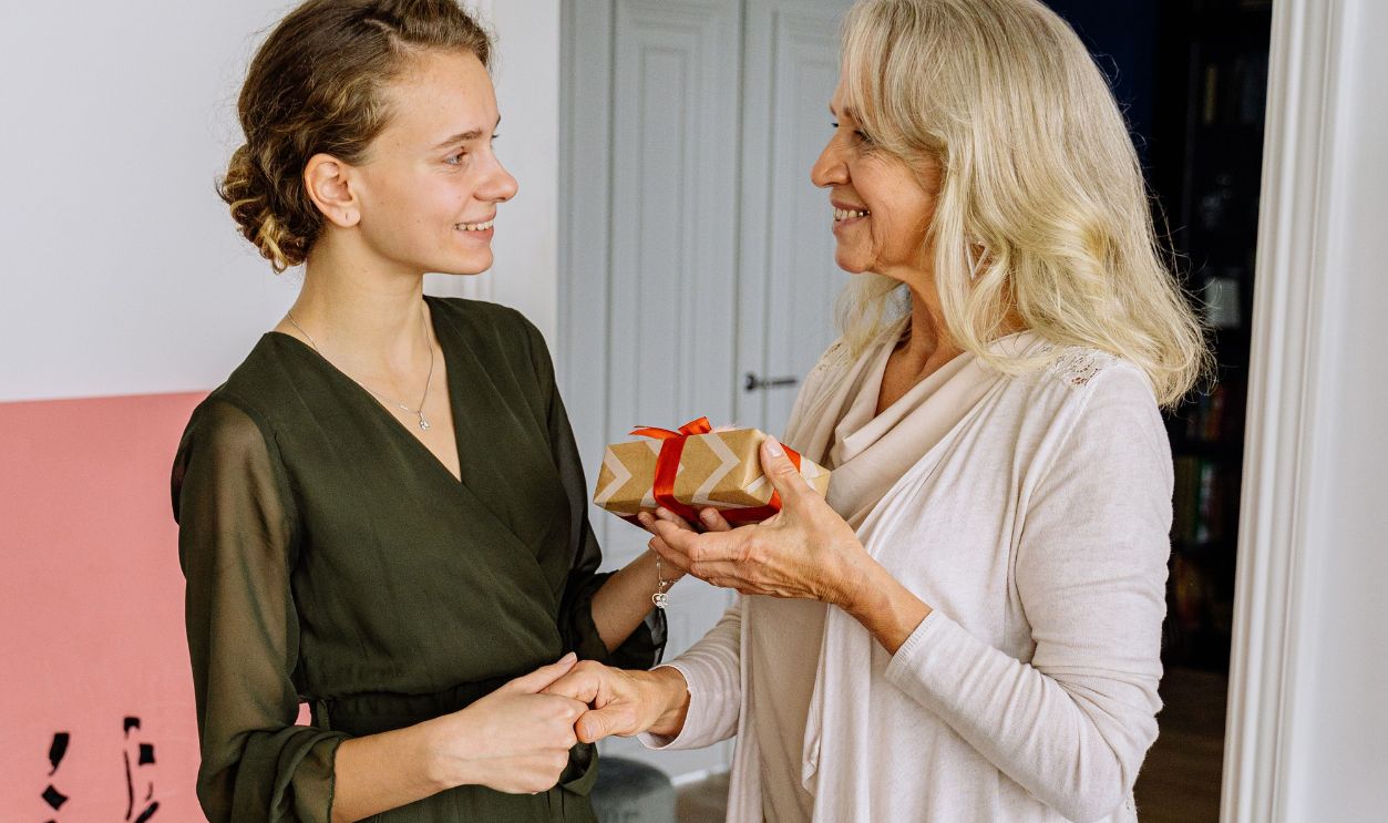 A joyful moment of gift exchange between mother and daughter during a festive meal.