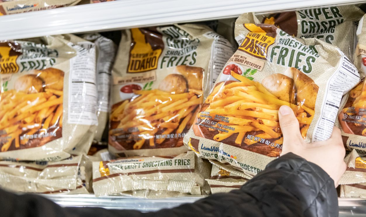 Los Angeles, CA/USA 3/12/2019 Human hand holding a package of Idaho grown brand frozen French fries in a supermarket freezer