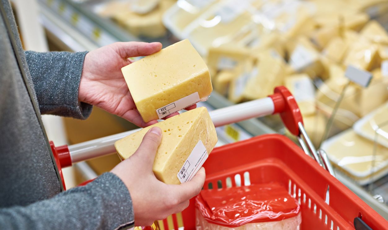 Hands of the buyer with a pieces of cheese in the store