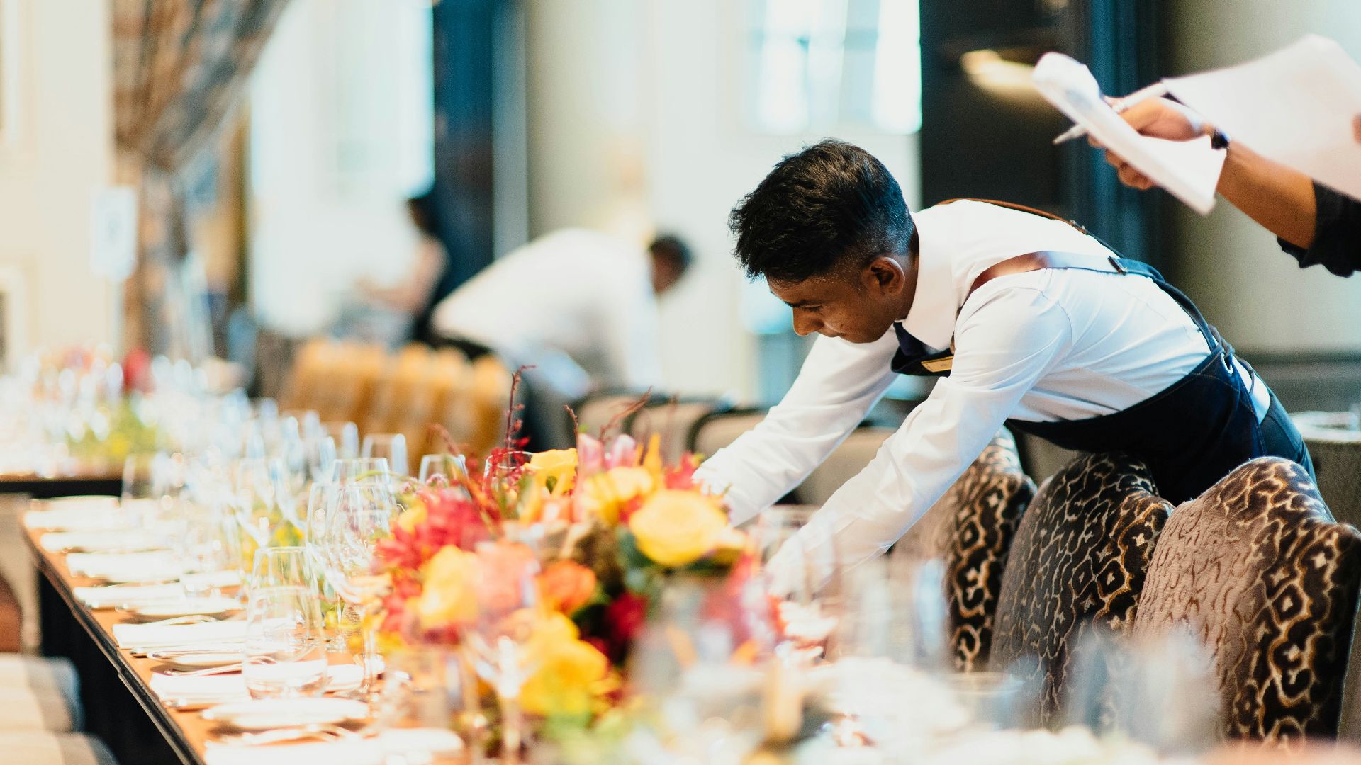 man in white top standing next to table