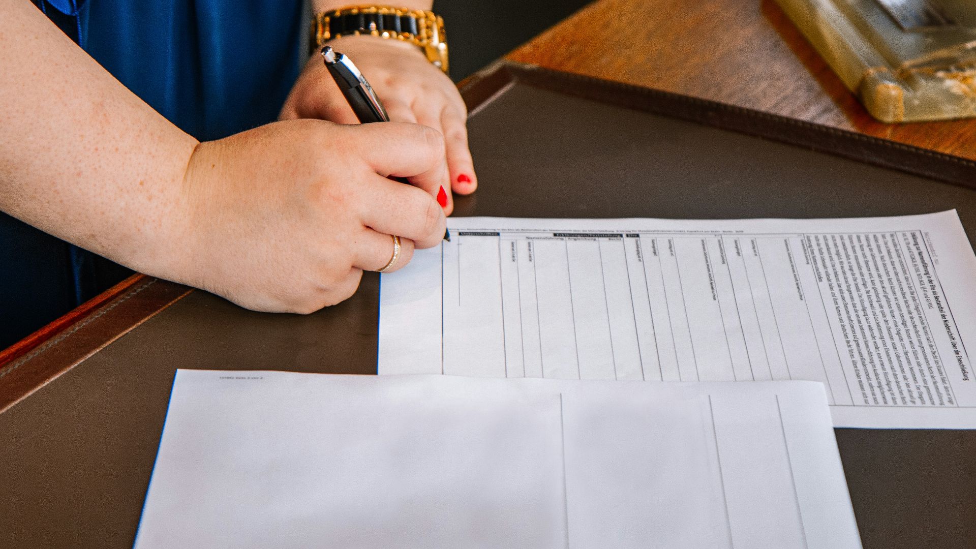 person holding pen and writing on paper