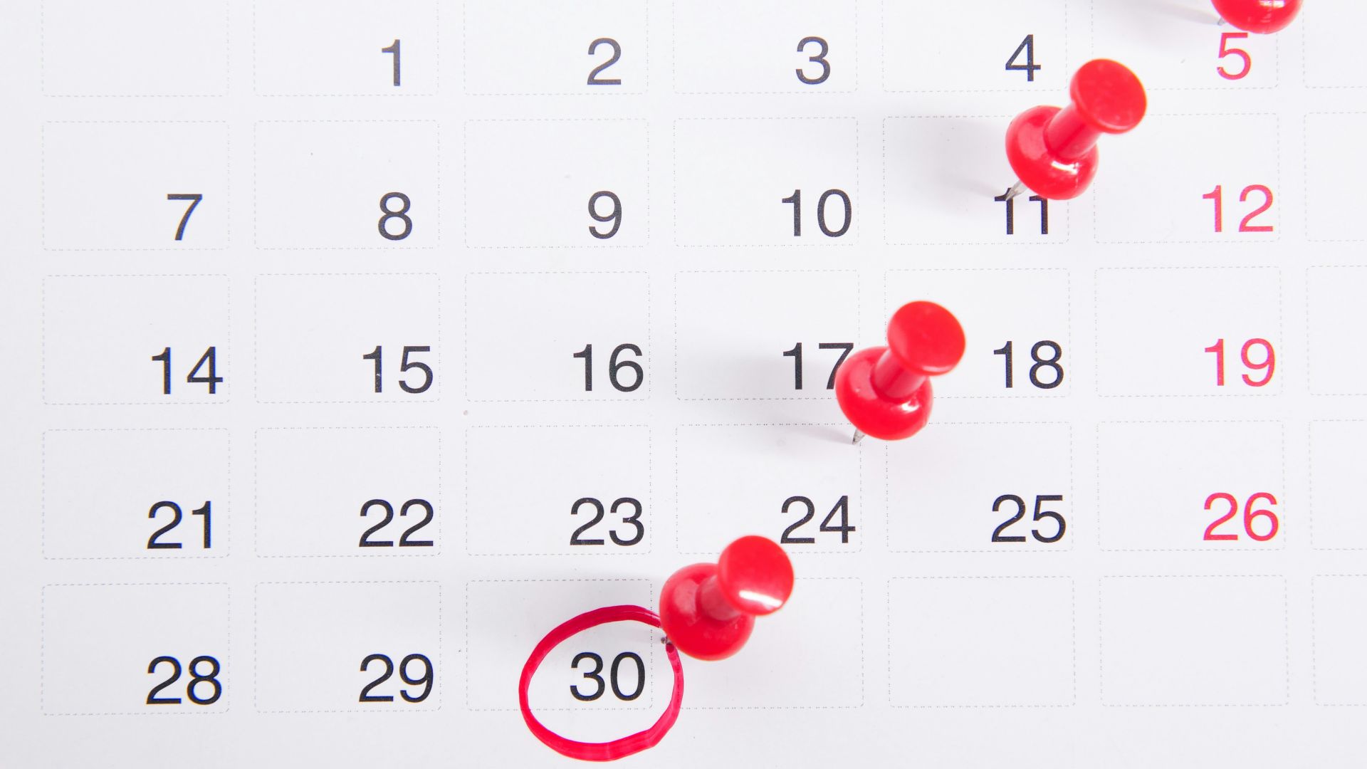 a calendar with red push buttons pinned to it